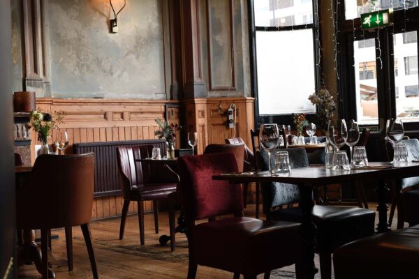 Characterful dining room with wooden panelling, leather chairs, set tables and large windows